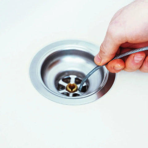 Hand Crank Drain Auger with quarter inch cable being inserted into sink drain, showing light duty plumber snake use.