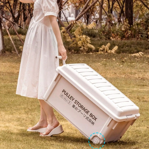 Heavy Duty Rolling Bin With Secure Lid And Easy Roll Casters, Stackable Outdoor Camp Organizer being pulled on grass.