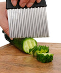 HTBMALL stainless steel crinkle cutter with black handle, close-up view slicing cucumber on a wooden cutting board