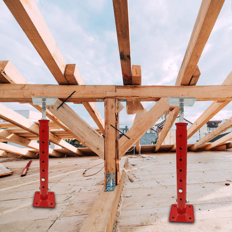 Two red adjustable basement floor jacks with screw threads supporting wooden framing
