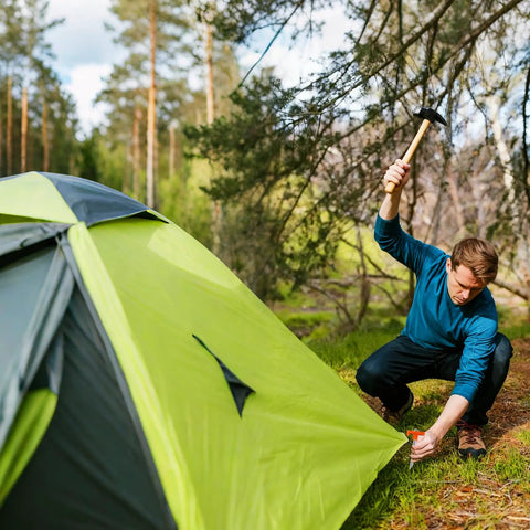 Man securing tent with Eight Pack Tent Stakes, Heavy Duty Galvanized Rustproof Ground Anchors For Canopies in an outdoor setting