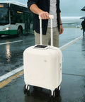 Mint Blue And Pearl White 18 Inch Carry On Suitcase With A Built In USB Charging Port and smartphone on top in the rain.