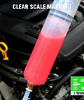 Close-up of a 200cc plastic fluid extractor syringe with pink liquid and blue tubing in a car engine bay.