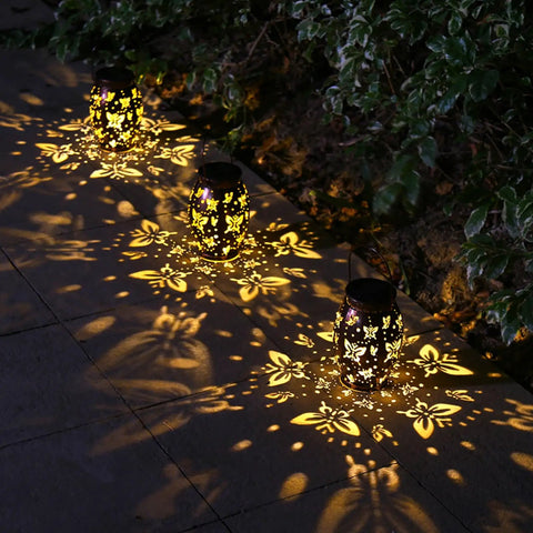 Butterfly Solar Powered Outdoor Metal Lanterns Set Of 2 Waterproof Hanging Patio Lights casting romantic shadows on pavement.