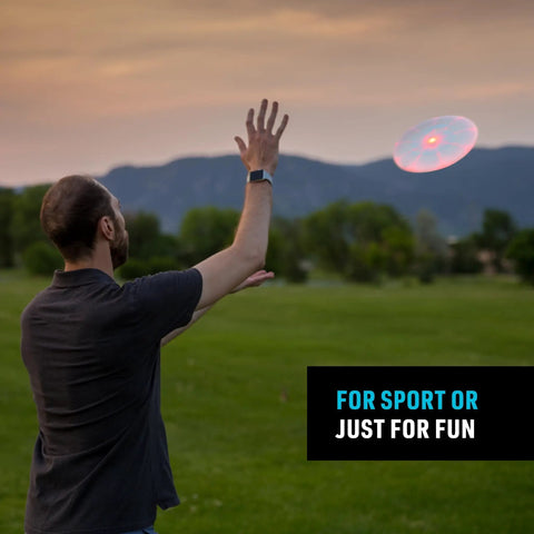 Man throwing Flashflight LED Light Up Frisbee Rechargeable Flying Disc with Disc O Tech at dusk in a park.