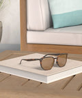 RB4306F Hexagonal Sunglasses With Light Havana Frame And Polarized B15 Brown Lenses resting on a book on a wooden table.