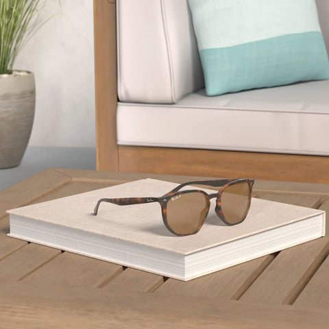 RB4306F Hexagonal Sunglasses With Light Havana Frame And Polarized B15 Brown Lenses resting on a book on a wooden table.