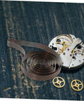 Mechanical Clock Spring For Alarm Clocks DIY Repairs And Craft Projects Replacement Component shown on wooden surface