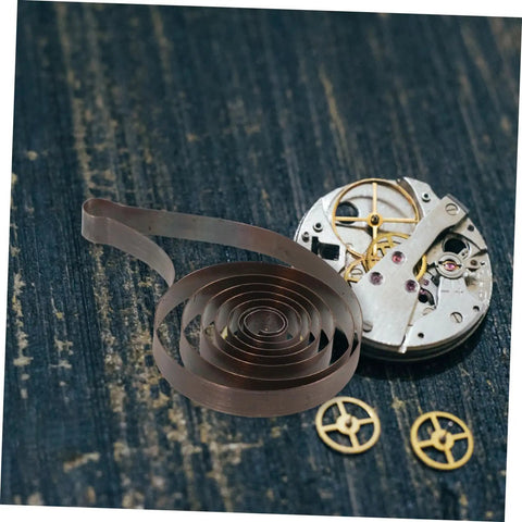 Mechanical Clock Spring For Alarm Clocks DIY Repairs And Craft Projects Replacement Component shown on wooden surface