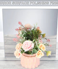 Pink ribbed ceramic vase with pastel artificial flowers in front of a large mirrored surface.