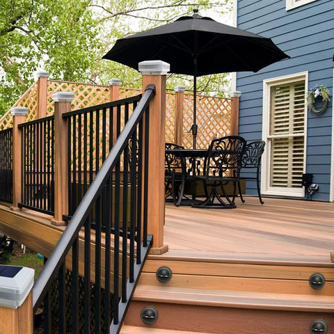 Wooden deck with 4x4 Solar Post Cap Lights, table with umbrella, and railing, showcasing deck lights for outdoor ambiance.