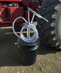 Lever Action 5 Gallon Pump For Oils And Lubricants, Self Priming, with 5 ft Hose on a Black Bucket beside Tractor Wheel