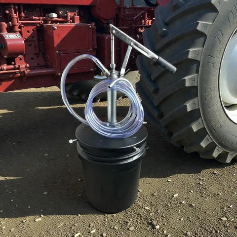Lever Action 5 Gallon Pump For Oils And Lubricants, Self Priming, with 5 ft Hose on a Black Bucket beside Tractor Wheel