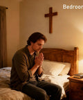 Person praying beside a wooden bed with a cross on the wall and a lamp and book on the nightstand in a bedroom.