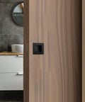 Installed Two And Three Quarters Inch Recessed Finger Flush Pocket Door Pulls in matte black stainless steel on wood door.