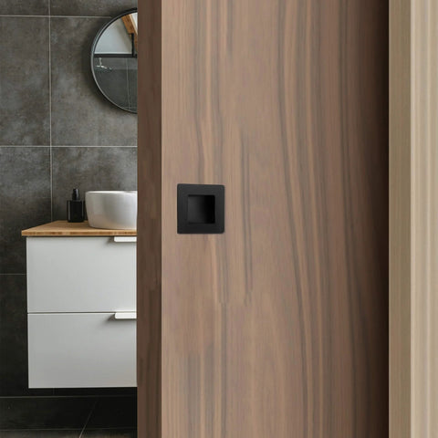 Installed Two And Three Quarters Inch Recessed Finger Flush Pocket Door Pulls in matte black stainless steel on wood door.