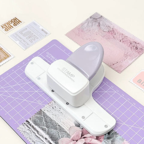 Adjustable Postage Stamp Border Punch For Scrapbooking And Card Making in mauve finish on craft table with stamp-like edges