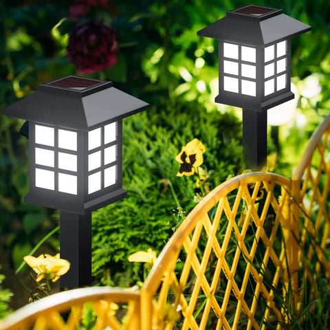 Solar Outdoor Lights 12 Pack Waterproof Pathway LED Landscape Lighting illuminating a garden pathway with plants.
