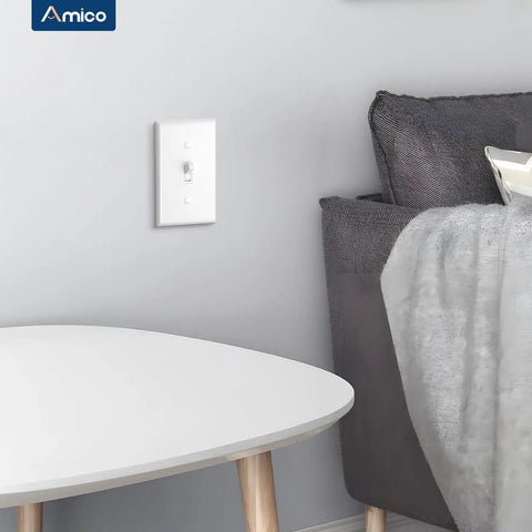 30 Pack UL Listed Toggle Light Switches With White Finish, Modern Classic Toggle Design For Any Room, Perfect For Living Rooms, Bedrooms, Kitchens And Hallways, Prevents Accidental Switching With Deliberate Pressure. White toggle switch on a bedroom wall beside a bed and side table.