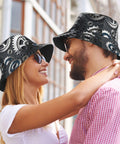 Fresh Unisex Black Bucket Hat With Dope Graphic Print And Super Lightweight Breathable Polyester Twill Fabric Easy Foldable Sun Hat For Chill Outdoor Vibes worn by couple outdoors.