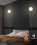 Plug In Wall Sconce With Globe Shade, Modern Indoor LED Wall Lamp in bedroom setting, showing soft warm white light from globe shade.