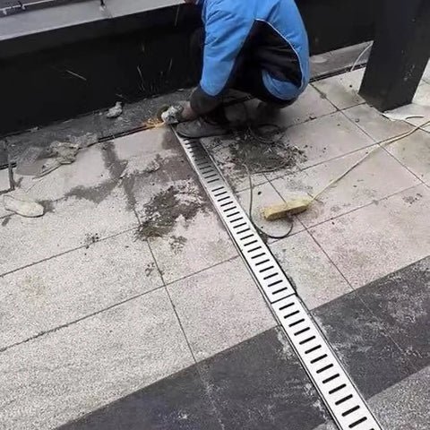 Worker installing Rock Solid 304 Stainless Steel Deck Drain Grates in outdoor setting, showing removable grid design.