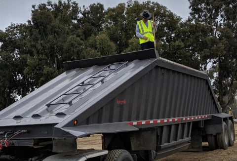 Worker wearing Vulcan Cowboy Style Hard Hat With Six Point Deluxe Nylon Ratchet Suspension stands on trailer.