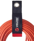 Heavy Duty Extension Cord Organizer With Large 18 Inch Straps For Slick Garage Wall Storage No Mess Setup Built Like A Tank Holds Solid One Hundred Pounds Includes Two Black Packs For Fast Wall Hook Or Nail Mounting, close-up of orange cord wrapped with Velcro strap.