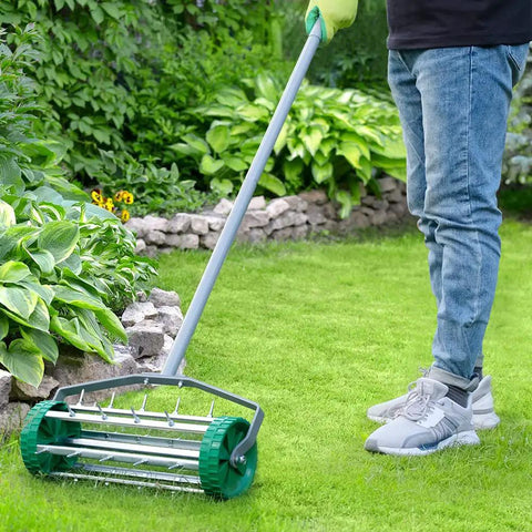 Pro Grade Spike Lawn Aerator With Heavy Duty Rolling Design For Lawn And Garden in use on green grass, steel handle visible