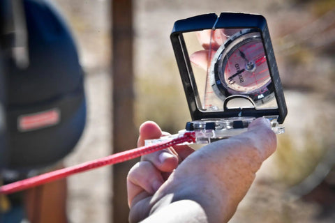 Close-up of Advanced Mirror Compass For Pros And Serious Hikers With Metric UTM Scales And Inch Ruler in use outdoors.
