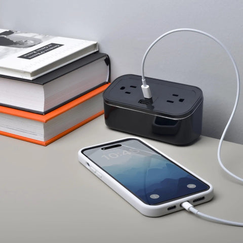 Compact Tabletop Power Strip Charging Station With 2 Tamper Resistant Outlets USB A And USB C Ports Rotated Plug Layout Ideal For Nightstands And Desks on desktop with phone and books