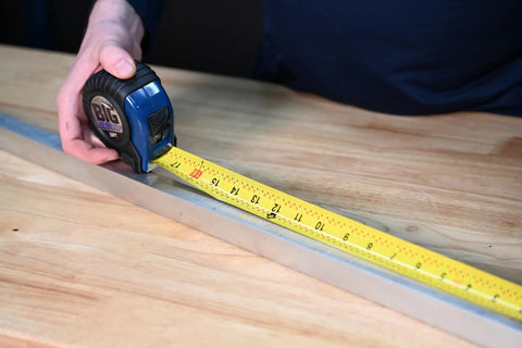 Person using Big Blue Tape Measure Thirty Three Feet With One And A Quarter Inch Wide Blade Easy Read Markings Pro Grade.