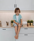 Child sitting on kitchen counter next to cabinets with 3 Inch Wide Foot Cabinet Pulls 10 Pack Matte Black Cabinet Handles installed