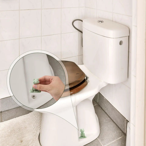 Kick Up Your Bathroom Style With These Pretty Dang Cute Ceramic Frog Toilet Bolt Cover Set Featuring Sturdy Tank Caps And Whimsical Hardware Accessories with a hand holding a frog cover.