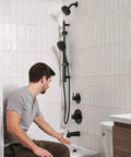 Man demonstrating Tub And Shower Trim Kit In Matte Black With 6 Function Shower Head, Easy Clean Nozzles, Full Body, Massage, Focus And Pause Settings, Reliable Valve Trim Upgrade For A Quick No Fuss Shower Refresh in bathroom.