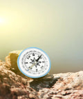 Big 100mm Pocket Compass for Camping and Hiking on a rock with sunlit background, durable ABS build, easy navigation outdoors.