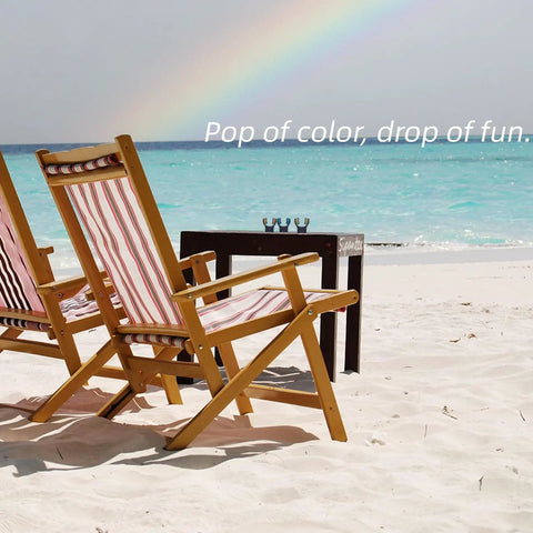 Two wooden beach chairs with striped fabric facing turquoise ocean and rainbow at horizon, sand and small table in foreground.
