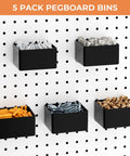 Five black pegboard bins mounted on white pegboard, holding orange wall anchors, screws, nuts, washers, and fittings.