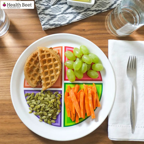 Choose MyPlate Four Section Portion Control Plate with waffle, grapes, pumpkin seeds, and carrots on wood table, 1 pack.
