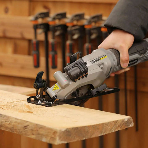 Inequalit gray mini circular saw, corded compact tool cutting wood on a workbench.