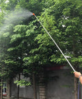 Person using Retractable Stainless Steel Sprayer Wand Extension Pipe Tool For Garden Farm And Horticulture Use, spraying trees