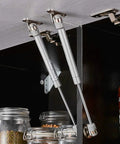 Heavy Duty 10 Inch Gas Spring Strut Lift Support With Brass Cover And Fixing Plate For Cabinet Doors Keeps Box Lids Open Smooth As Butter 60N Silent Glide No Slam Shut Hardware mounted inside a kitchen cabinet.