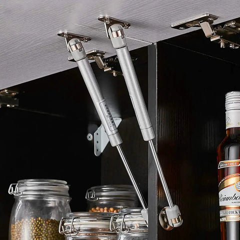 Heavy Duty 10 Inch Gas Spring Strut Lift Support With Brass Cover And Fixing Plate For Cabinet Doors Keeps Box Lids Open Smooth As Butter 60N Silent Glide No Slam Shut Hardware mounted inside a kitchen cabinet.