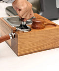 Premium Wood Coffee Tamping Station With Integrated Knock Box And Non Slip Tamper Pad For 58Mm Portafilter in use, showing tamping process.
