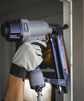 Worker using Pneumatic 16 Gauge Straight Finish Nailer With 2000 Nails Pro Grade Lightweight Aluminum Body Easy Load For One To Two And A Half Inch Nails Built For Trim Molding Crown Molding Baseboards Window Casing Furniture And DIY Projects on window casing.