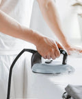 Person ironing with heavy duty high temperature steam hose for steam irons and high pressure ironing, durable tubing visible.