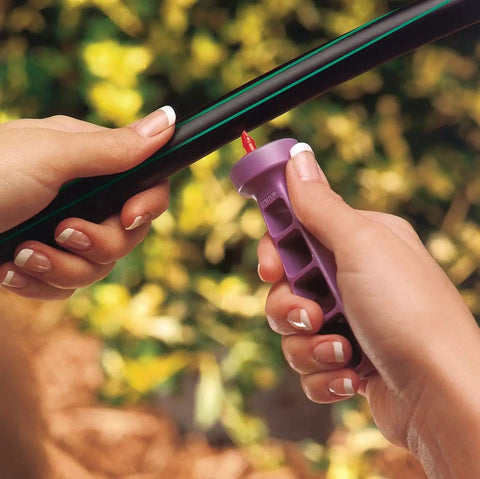 Hands holding a tool for Drip Irrigation Repair And Expansion Kit With 102 Universal Parts, 100 Feet Self Dispensing Tubing