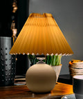 Pleated Ceramic Table Lamp With Tricolor Led Bulb For Living Room Decor on a wooden table with warm light glow