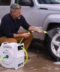 Man using Heavy Duty Retractable Water Hose Reel With Half Inch By Seventy Feet Hose Auto Rewind Latching Length Control Or Free Run Seven Position Swivel Bracket Locks At 135 Degrees Durable Garden Essential For Quick Yard Watering Beast Yard Favorite to wash a car.