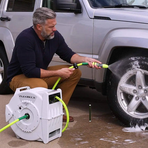 Man using Heavy Duty Retractable Water Hose Reel With Half Inch By Seventy Feet Hose Auto Rewind Latching Length Control Or Free Run Seven Position Swivel Bracket Locks At 135 Degrees Durable Garden Essential For Quick Yard Watering Beast Yard Favorite to wash a car.